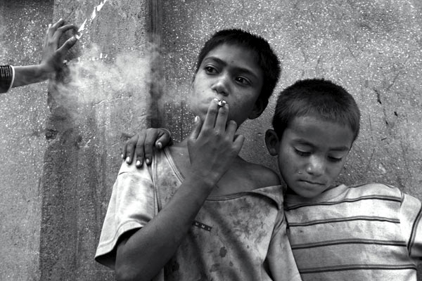 Bikash seen smoking and brother Deepak are street kids in Kathmandu, Nepal.  It is estimated that over 600 children live and work on the streets in the Kathmandu valley.  Most are orphaned, discarded, or escaped their villages when the Maoists tried to recruit them.  June 2005.