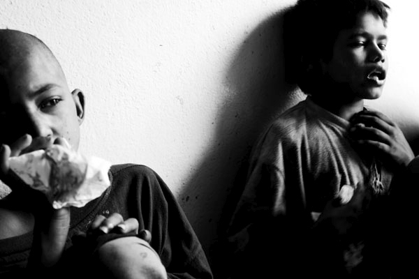Santos and Raju inhale glue in an alleyway in Kathmandu, Nepal.  The continued use of glue effects neurological and are long term.  Santos says it helps take away hunger, cold and while hallucinating he sees the Hindu God Ganesh.  June 2005.