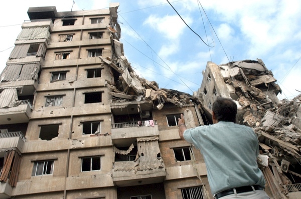 17 August 2006, Lebanon, Beirut, Dahia. 2006 Lebanon War. Unidentified man looks at the destroyied buildings while talking on the phone.    