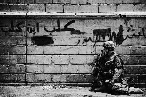 A soldier rests on the streets of Sadr City, Iraq during a dismounted security patrol June, 2008.  Most soldiers and Marines work over ten (and up to 20 or more) hours a day, seven days a week in temperatures reaching 60c/140f.  To add to the physical stress, body armor weighs around 18kg/40lbs and combined with other equipment they often carry a total of 31kg/70lbs.  The mental stress also weighs on soldiers and Marines, as most of their time outside of bases is spent trying to guess who may be friendly and who may be their enemy.